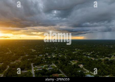 Bei Sonnenuntergang bilden sich dunkle, ominöse Wolken am stürmischen Himmel während eines schweren Gewitters über dem ländlichen Stadtgebiet. Stockfoto