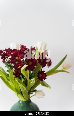 Bouquet von Tulpen und Chrysanthemen in einer Vase auf weißem Hintergrund. Stockfoto