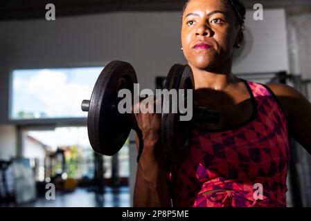 Dramatisches Porträt einer Fitness-Frau, die Armmuskeltraining macht. Fitness-Training. Stockfoto