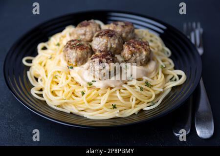 Schwedische Noisettes (Fricandel) mit Spaghetti und Brune Sos cremige Sauce. Traditionelle Fleischbällchen mit Garnierung. Selektiver Fokus, Nahaufnahme. Stockfoto