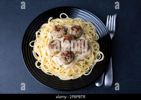 Schwedische Noisettes (Fricandel) mit Spaghetti und Brune Sos cremige Sauce. Traditionelle Fleischbällchen mit Garnierung. Selektiver Fokus, Draufsicht, Nahaufnahme. Stockfoto