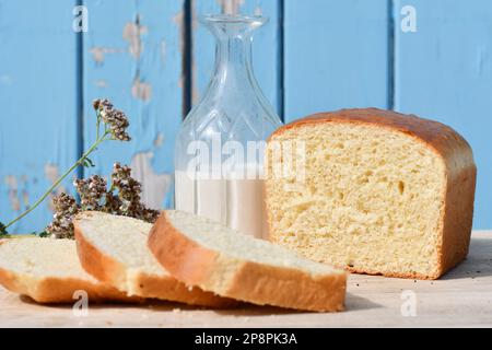 Geschnittenes Brot auf einem Schneidebrett mit blauem Holzhintergrund Stockfoto