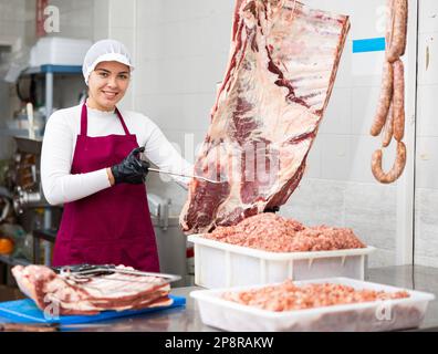 Junge Metzgerin mit Rinderrippchen Stockfoto