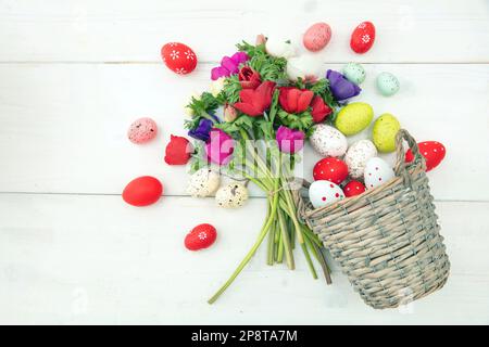 Mohnblume und Ostereier in einem Korb aus Korb, weißer Holztisch-Hintergrund, Kopierbereich. Stockfoto