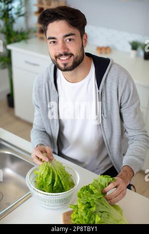 Mann mischt vegetarische Zutat in einen Topf Stockfoto