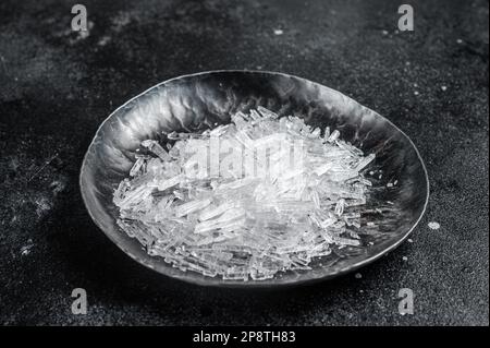 Menthol-Kristalle in einer kleinen Stahlplatte. Schwarzer Hintergrund. Draufsicht. Stockfoto