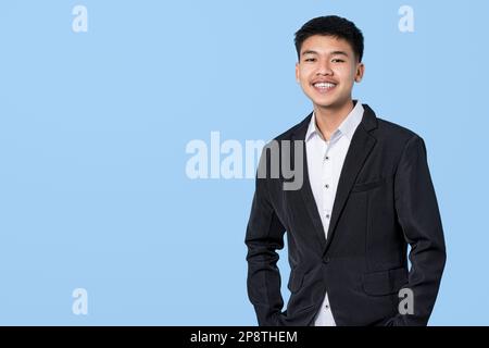Junger, gutaussehender asiatischer Geschäftsmann, der selbstsicher lächelt, isoliert auf blauem Hintergrund. Konzept für Geschäftsleute. Stockfoto