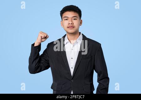 Ein junger, gutaussehender asiatischer Geschäftsmann, der sich auf Erfolg gefeiert hat, isoliert auf blauem Hintergrund Stockfoto