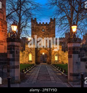 Blick von außen in der Abenddämmerung auf das Gatehouse zum Durham Castle, das unter klarem Himmel im Frühling beleuchtet wird, Stadt durham, County Durham, England, Großbritannien Stockfoto