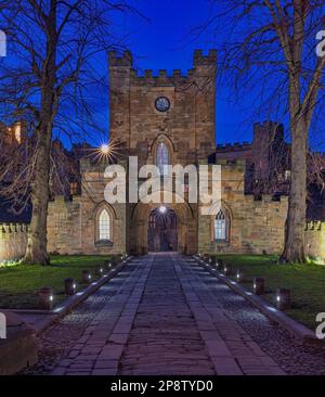 Blick von außen in der Abenddämmerung auf das Gatehouse zum Durham Castle, das unter klarem Himmel im Frühling beleuchtet wird, Stadt durham, County Durham, England, Großbritannien Stockfoto