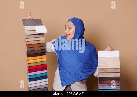 Muslimische Frau in Hidschab, Verkaufsberaterin im Möbelgeschäft, die Kunden bei der Auswahl von Polstermaterialien hilft Stockfoto