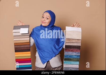 Erfolgreiche arabische muslimische Frau im Hijab, Innenarchitekt, präsentiert Stoffmuster für die Sofabonpolsterung Stockfoto