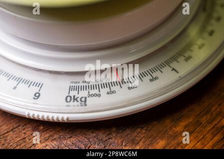 Mechanische Küchenwaage auf Holzhintergrund. Messung des Gewichts von Produkten zum Kochen. Auf einer Waage mit einem Gewicht von 600 Gramm Stockfoto