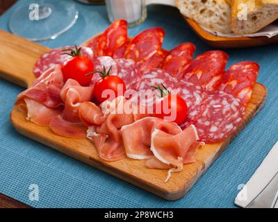 Spanische leckere Mahlzeit Würste und Jamon mit Tomaten schneiden, Nahaufnahme Stockfoto