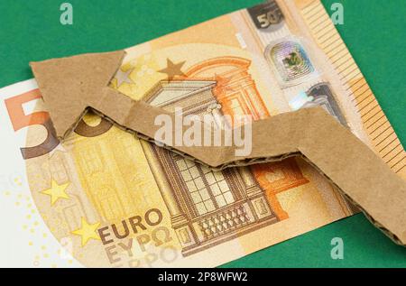 Euro-Banknoten und ein nach oben zeigender Papppfeil liegen auf einer grünen Oberfläche. Wirtschaftswachstum. Stockfoto