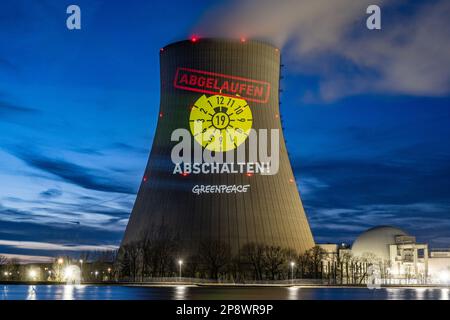 Niederaichbach, Deutschland. 09. März 2023. Greenpeace-Aktivisten projizieren einen abgelaufenen HU-Aufkleber auf den Kühlturm des Atomkraftwerks Isar 2. Die Aktivisten machen mit ihrem Handeln darauf aufmerksam, dass 2019 für drei Kernkraftwerke eine Sicherheitsüberprüfung fällig gewesen wäre, die aber noch nicht durchgeführt wurde. Kredit: Armin Weigel/dpa/Alamy Live News Stockfoto