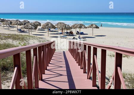 Treppen zum tropischen Strand mit weißem Sand, Korbschirmen und Sonnenbänken. Malerischer Blick auf die Küste, Touristenresort auf der Karibikinsel Stockfoto