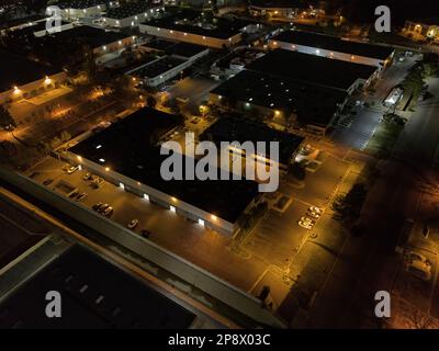 Unscheinbare Lager und Bürogebäude werden in einem Gewerbepark bei Nacht aus der Sicht von oben gezeigt. Stockfoto