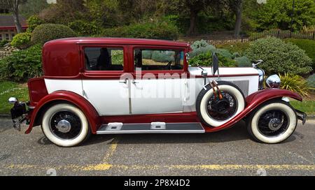 FELIXSTOWE, SUFFOLK, ENGLAND - 01. MAI 2022: Klassischer Rot- und Creme-Nash-Ambassador-Wagen isoliert vor den Gärten. Stockfoto