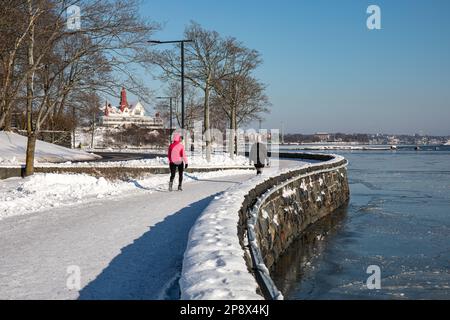 Menschen, die an einem sonnigen Wintertag auf der Ehrenströmintie Promenade im Kaivopuisto-Viertel von Helsinki, Finnland, spazieren gehen Stockfoto