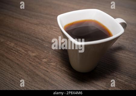 Tasse mit heißem schwarzen Kaffee auf Holzhintergrund Stockfoto