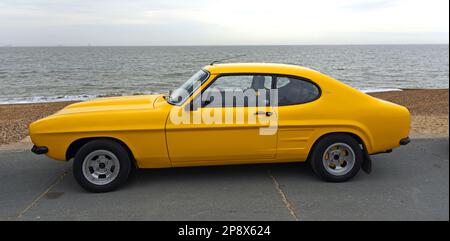 FELIXSTOWE, SUFFOLK, ENGLAND - 01. MAI 2022: Klassischer gelber Ford Capri GT parkt an der Uferpromenade im Hintergrund. Stockfoto