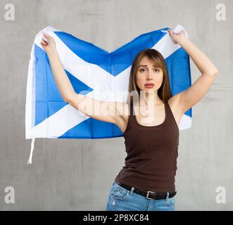 Aufgebrachte Frau mit schottischer Flagge auf grauem Hintergrund Stockfoto