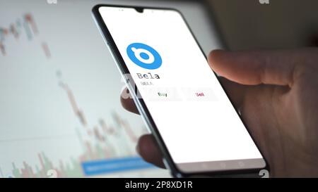 Ein Investor analysiert die Bela ( )-Münze auf dem Bildschirm. Ein Telefon zeigt die Preise der Kryptos für die Investition in Ampere-Token an. Stockfoto