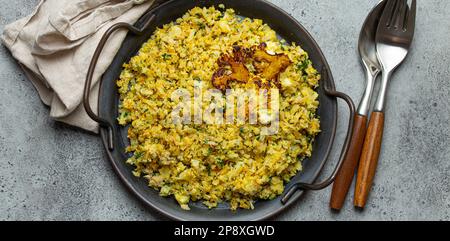 Gebratener Blumenkohl-Reis oder Couscous mit Dill auf dem Teller, gesunde kohlenhydratarme Gemüse-Beilage für Keto-Diät und gesunde kalorienarme Ernährung Stockfoto