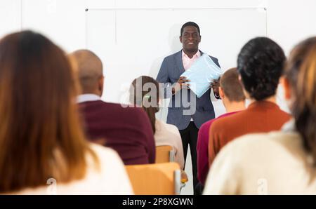 afroamerikanischer Coach Geschäftsmann, der auf einer modernen Bürokonferenz ein Gespräch mit einem multiethnischen Team führt Stockfoto