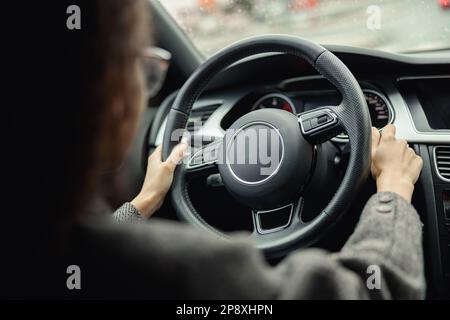 Rückansicht der Frau, die während der Stadtfahrt den Blinker im Auto benutzt Stockfoto