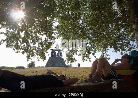 Pilger, die sich in Monte del Gozo ausruhen. Ein Denkmal im Hintergrund, das dem Besuch von Papst johannes paul II. Gewidmet ist Provinz Coruña.Spanien. Camino de Santiago. lu Stockfoto