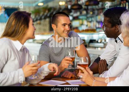 Verschiedene Freunde, die sich in einem Pub unterhalten und lächeln Stockfoto