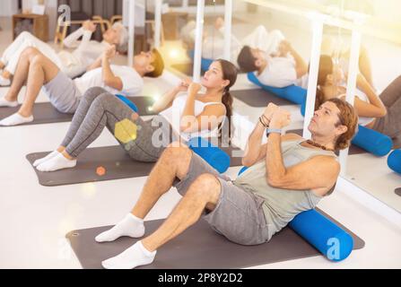 Gruppe von Personen, die im Fitnessstudio Hüftbrücken-Übungen machen Stockfoto