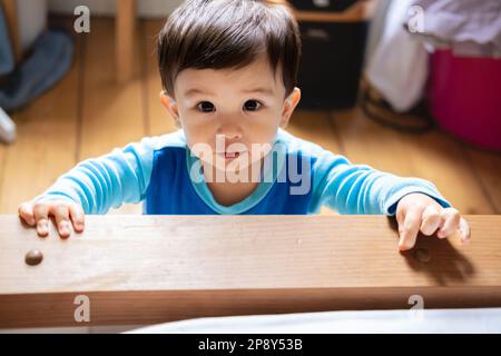 Ein multirassisches malaysisches und spanisches Baby, das blauen Pyjama trägt und mit Schleim unter der Nase in die Kamera starrt, weil es krank und krank ist. Berühren Stockfoto