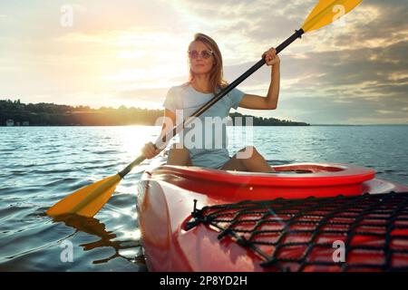 Wunderschöne Frau, die Kajak auf dem Fluss fährt. Sommeraktivität Stockfoto