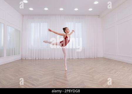 Kleine Ballerina, die Tanzbewegungen im Studio praktiziert Stockfoto