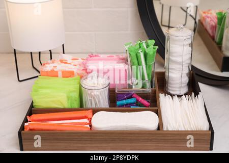Holzorganisator mit verschiedenen Damenhygieneprodukten auf dem Tisch Stockfoto