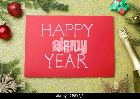 Frohe Neujahrskarte. Rotes Papier mit Phrase und Dekor auf glänzendem Hintergrund, flach gelegt Stockfoto