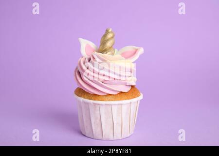 Süßer, süßer Einhorn-Cupcake auf violettem Hintergrund Stockfoto