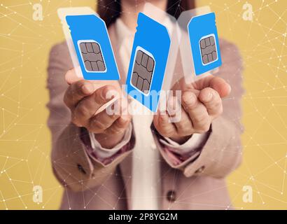 Frau, die SIM-Karten verschiedener Größen auf gelbem Hintergrund vorführt, Nahaufnahme Stockfoto