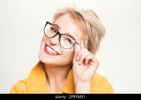 Optiken Store. Modische Brillen. Lächelnde blonde Frau trägt eine Brille aus nächster Nähe. Brillenmode. Fügen Sie intelligentes Zubehör hinzu. Stilvolle Mädchen mit Stockfoto