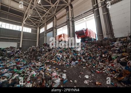 Der Müllwagen entlädt den Hausmüll in der Eingangskammer einer Abfallsortieranlage Stockfoto