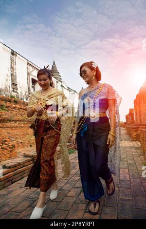 Zwei asiatische Frauen in altem thailändischem Anzug wandern im ayutthaya-Tempel, einer der UNESCO-Weltkulturerbestätten in thailand Stockfoto