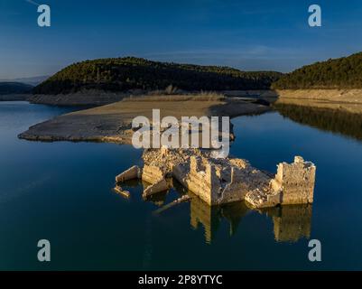 Blick aus der Vogelperspektive auf ein altes Haus in Ruinen, das durch den niedrigen Wasserstand des Sant Ponc Reservoirs (Solsonès, Lleida, Katalonien, Spanien) geschützt ist Stockfoto