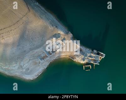 Blick aus der Vogelperspektive auf ein altes Haus in Ruinen, das durch den niedrigen Wasserstand des Sant Ponc Reservoirs (Solsonès, Lleida, Katalonien, Spanien) geschützt ist Stockfoto