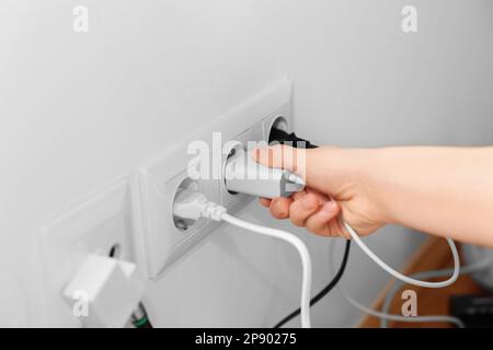 Frau, die zu Hause den Stecker in die Steckdose steckt, Nahaufnahme Stockfoto