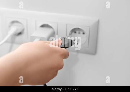 Frau, die zu Hause den Stecker in die Steckdose steckt, Nahaufnahme Stockfoto