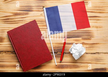 Französische Flagge mit Notizbuch, Stift und zerknittertem Papier auf Holzhintergrund Stockfoto