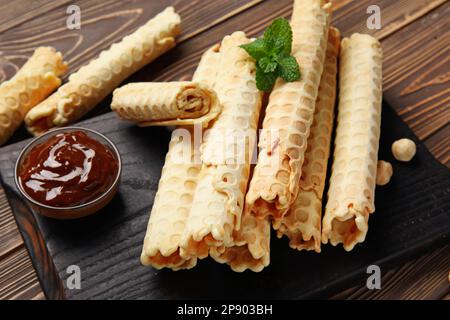 Gehen Sie an Bord mit köstlichen Waffeln, gekochter Kondensmilch und Haselnüssen auf braunem Holzhintergrund Stockfoto